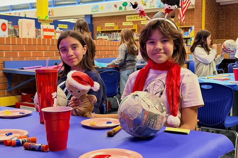 Two girls smile with their papier mache creations