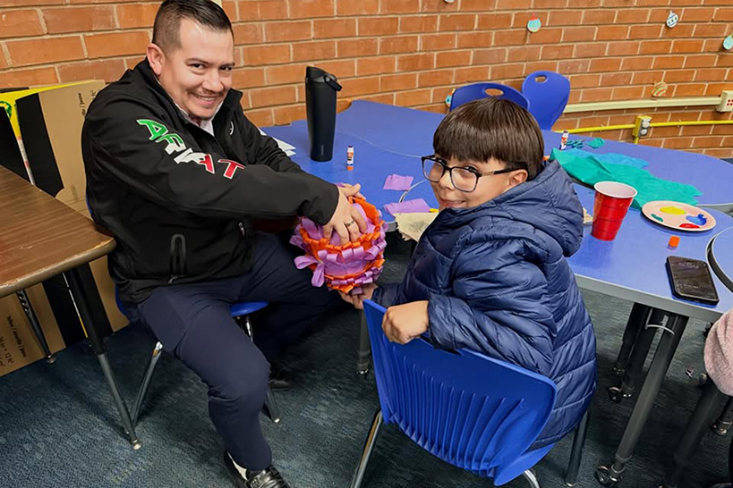 A dad and his son show off the boy's colorful art creation