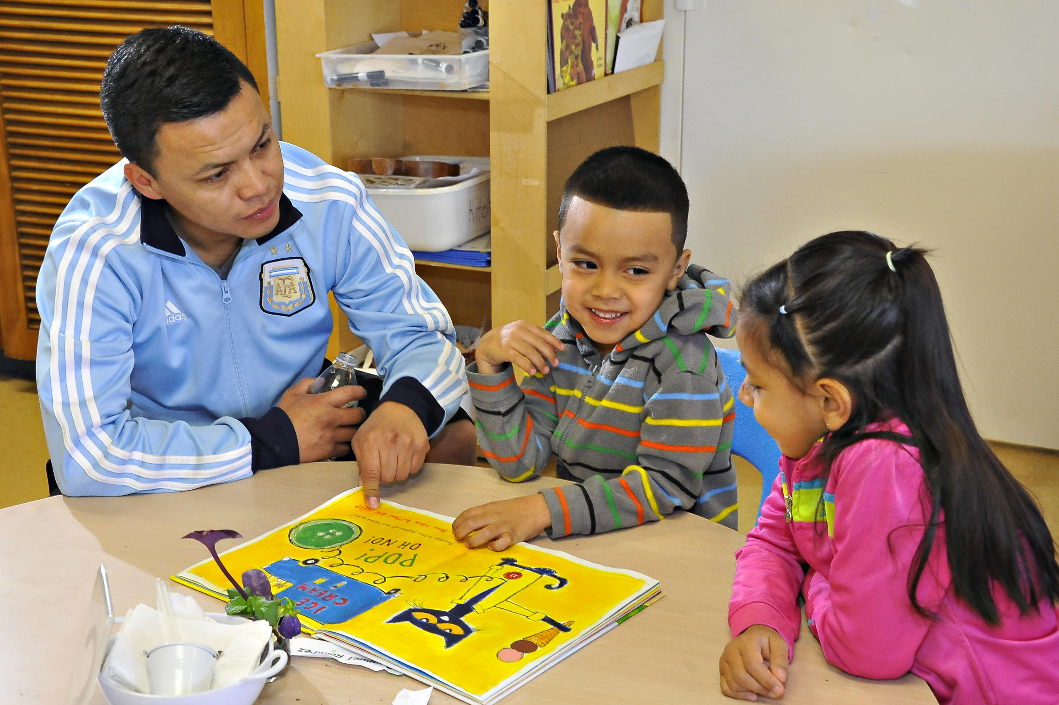 A boy and girl work on a project while their teacher helps them